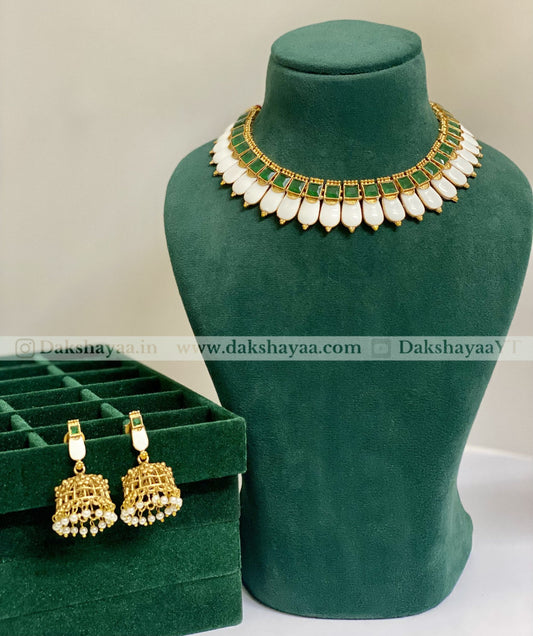 Jewelry set with necklace and earrings on a green mannequin and box, brand 'Dakshayaa' visible.
