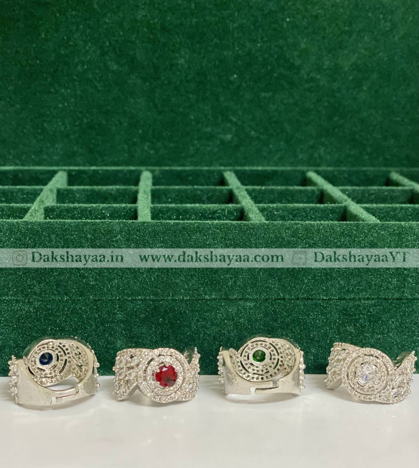 Four silver rings with gemstones on a green velvet background