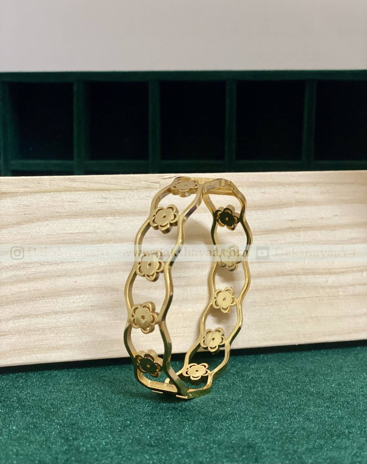 Gold bracelet with floral designs on a white surface