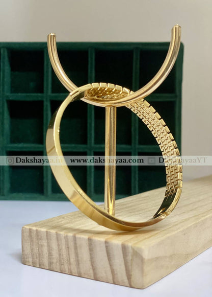 Gold kada on a wooden stand with a green shelving unit in the background