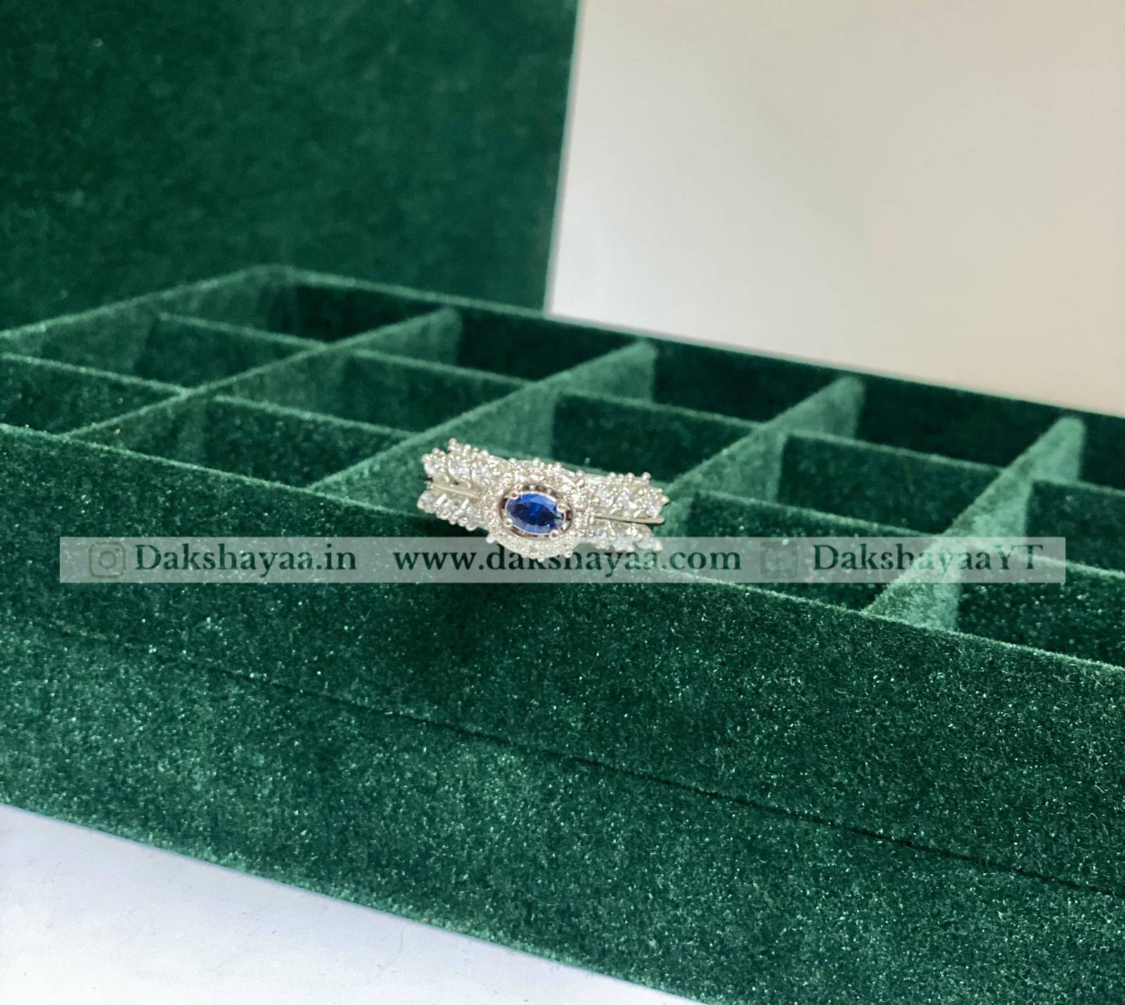 Silver ring with a blue gemstone on a green jewelry box