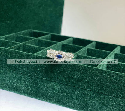 Silver ring with a blue gemstone on a green jewelry box