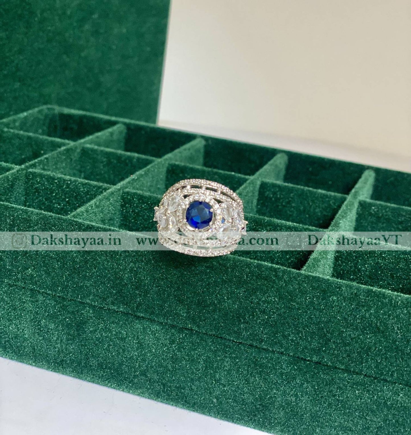 Silver ring with a blue gemstone on a green jewelry display box