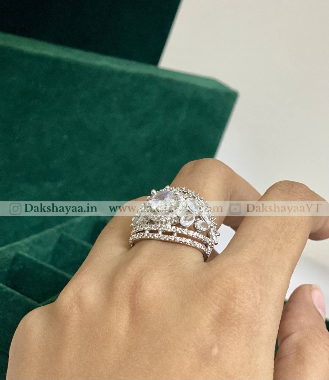 Three silver rings on a finger with a green box in the background