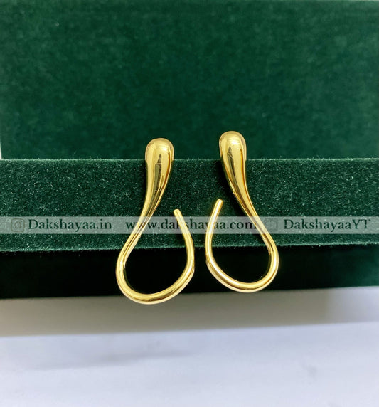 Gold earrings on a green and white background