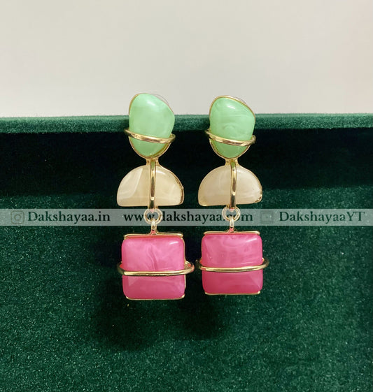 Pair of earrings with green and pink stones on a green background