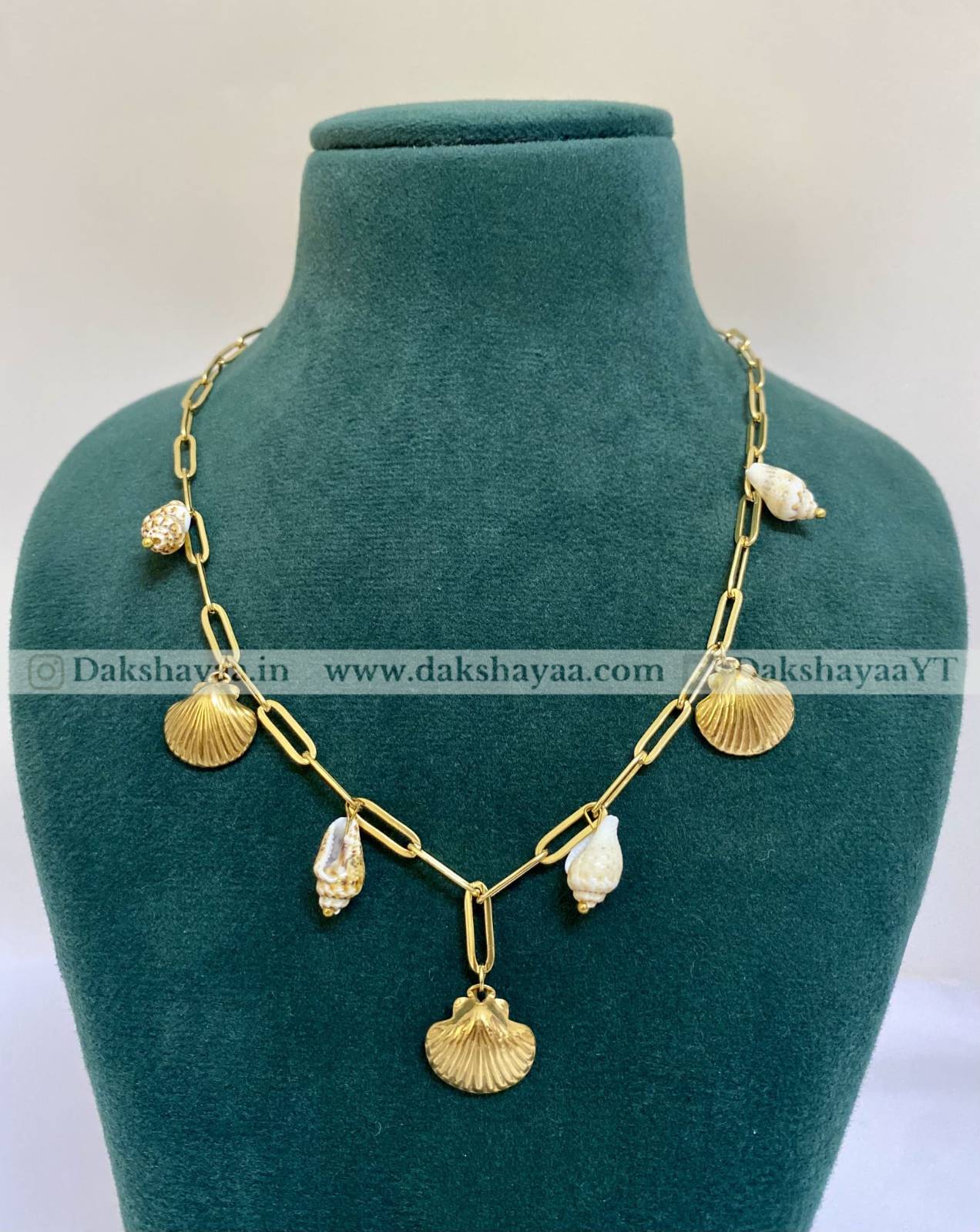 Gold necklace with shell-like pendants on a green mannequin