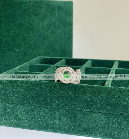 Silver ring with a green gemstone on a green velvet box