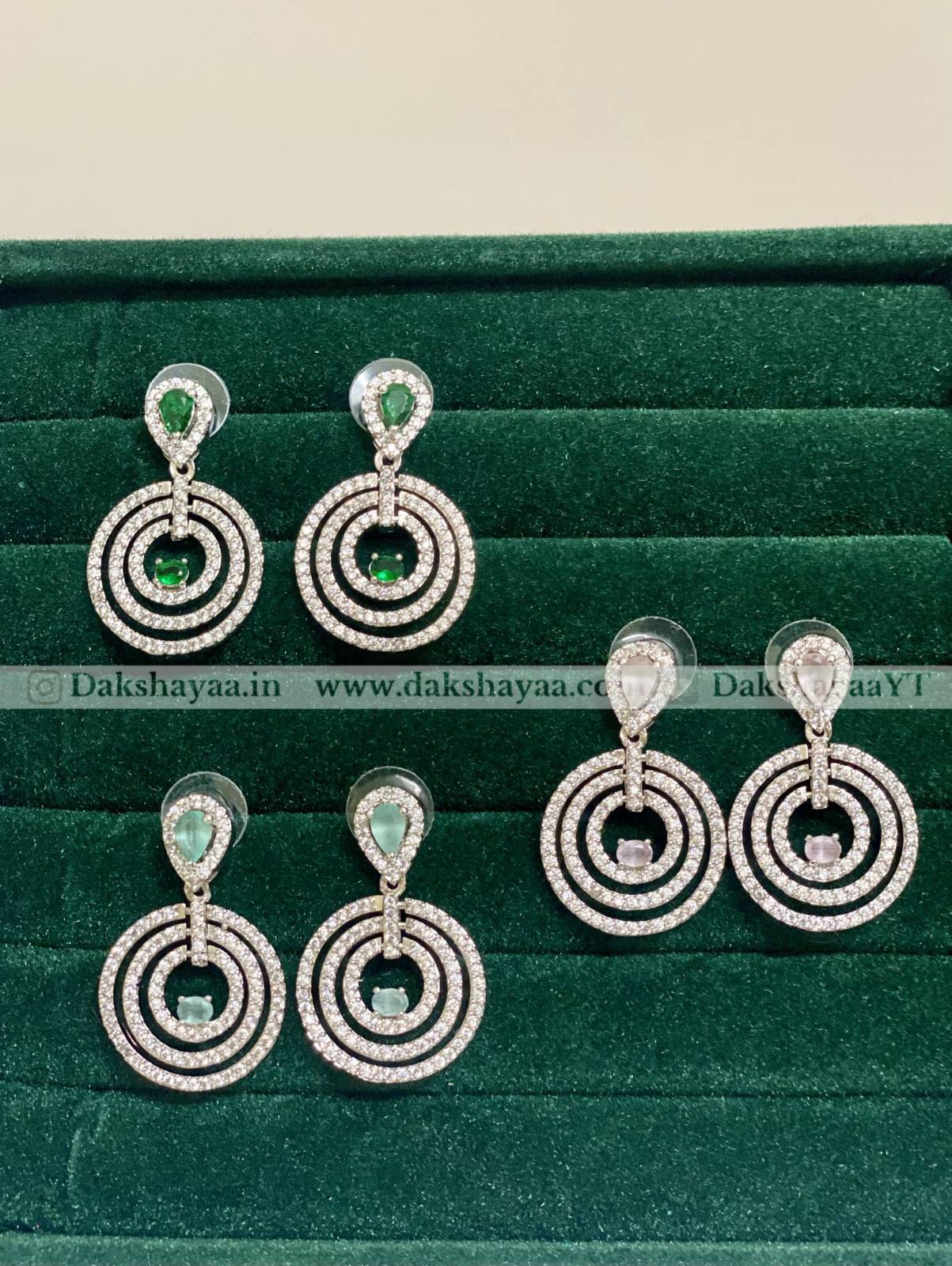Pair of silver earrings with green gemstones on a green velvet background