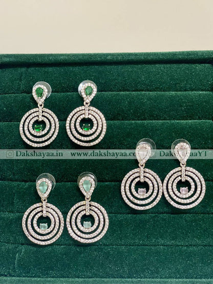 Pair of silver earrings with green gemstones on a green velvet background
