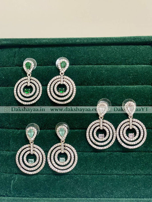 Pair of silver earrings with green gemstones on a green velvet background