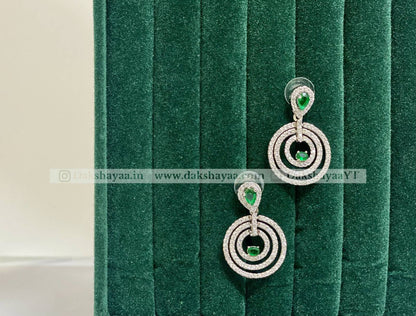 Pair of silver earrings with green gemstones on a green velvet background