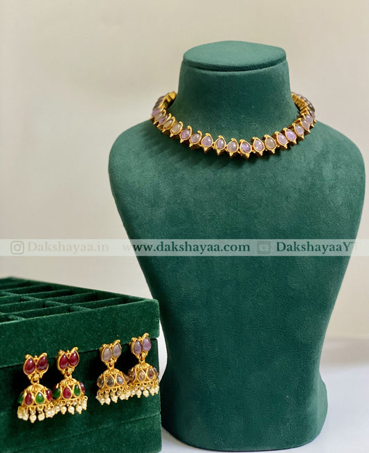 Gold necklace and earrings on a green mannequin with 'Dakshayaa' branding.