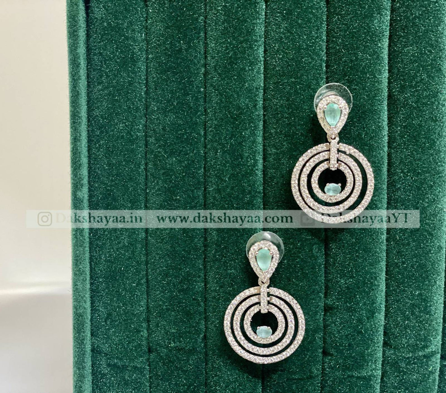 Silver earrings with green gemstones on a green velvet background