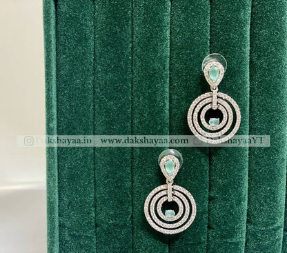 Silver earrings with green gemstones on a green velvet background