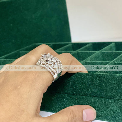 Silver ring with a large diamond on a hand against a green velvet background