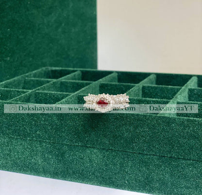 Jewelry box with a ring featuring a red gemstone on a green background