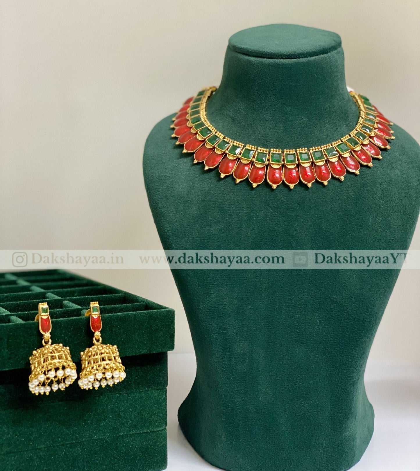 Jewelry set with necklace and earrings on a green mannequin and box, featuring red and gold colors.