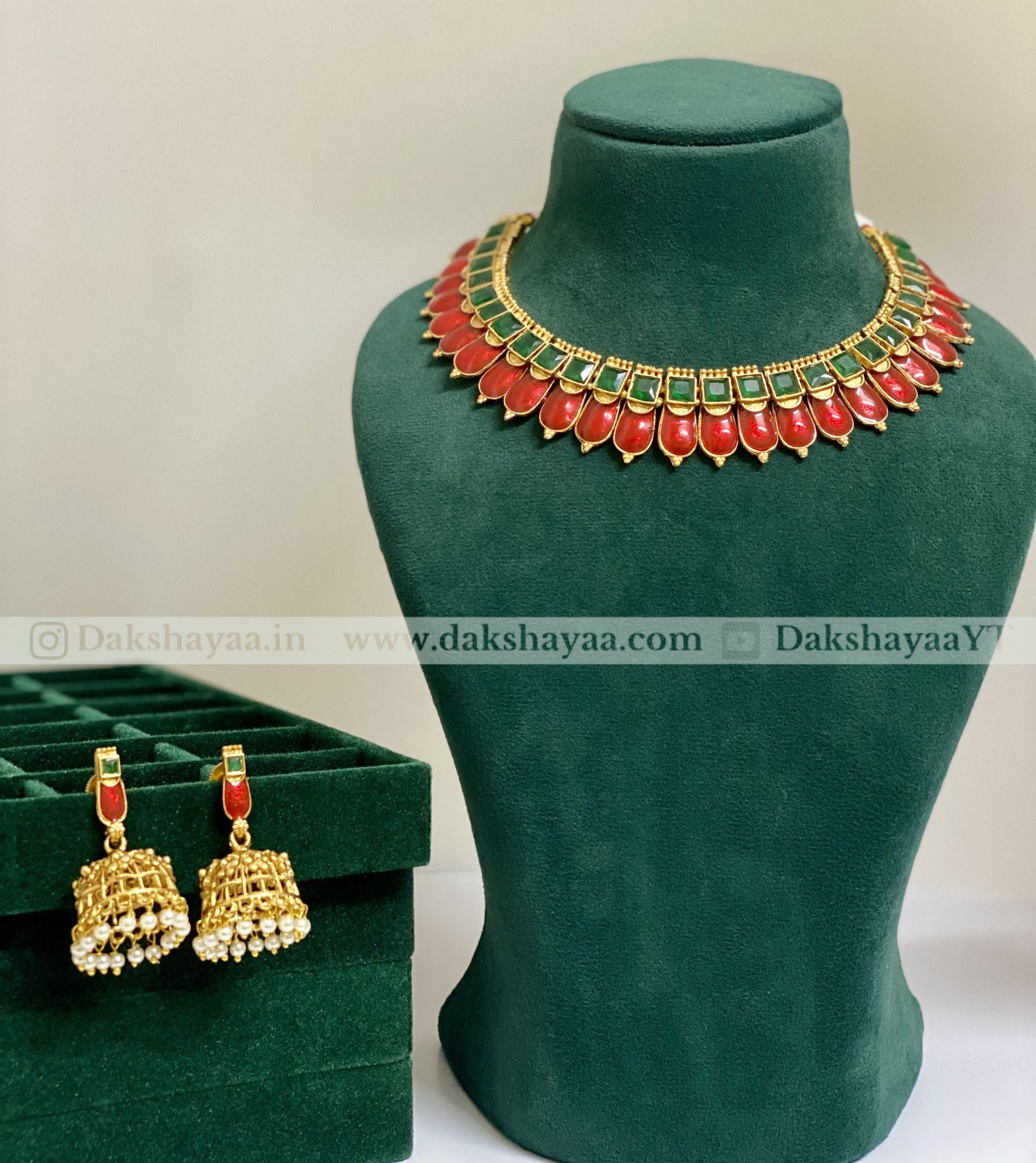 Jewelry set with necklace and earrings on a green mannequin and box, featuring red and gold colors.