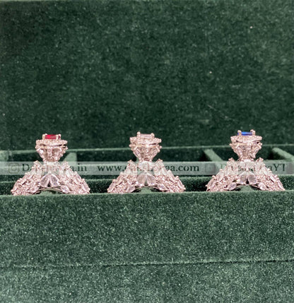 Three diamond earrings on a green cushion with a blurred background