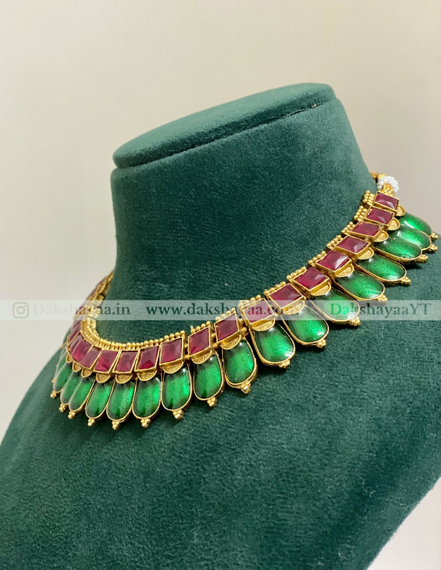 Green and red gemstone necklace on a green velvet stand