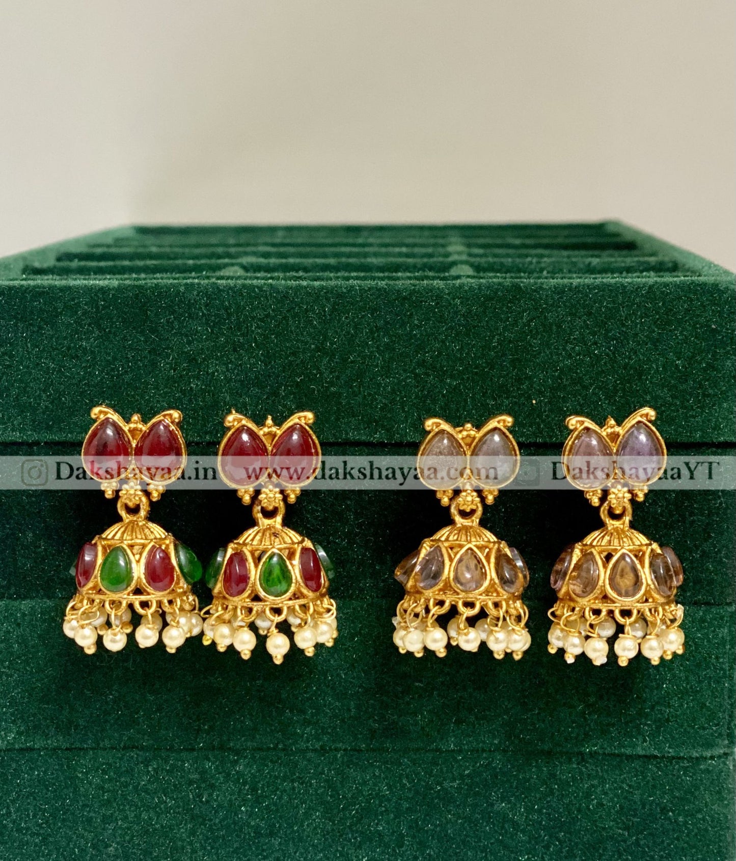 Set of gold earrings with gemstones on a green velvet background