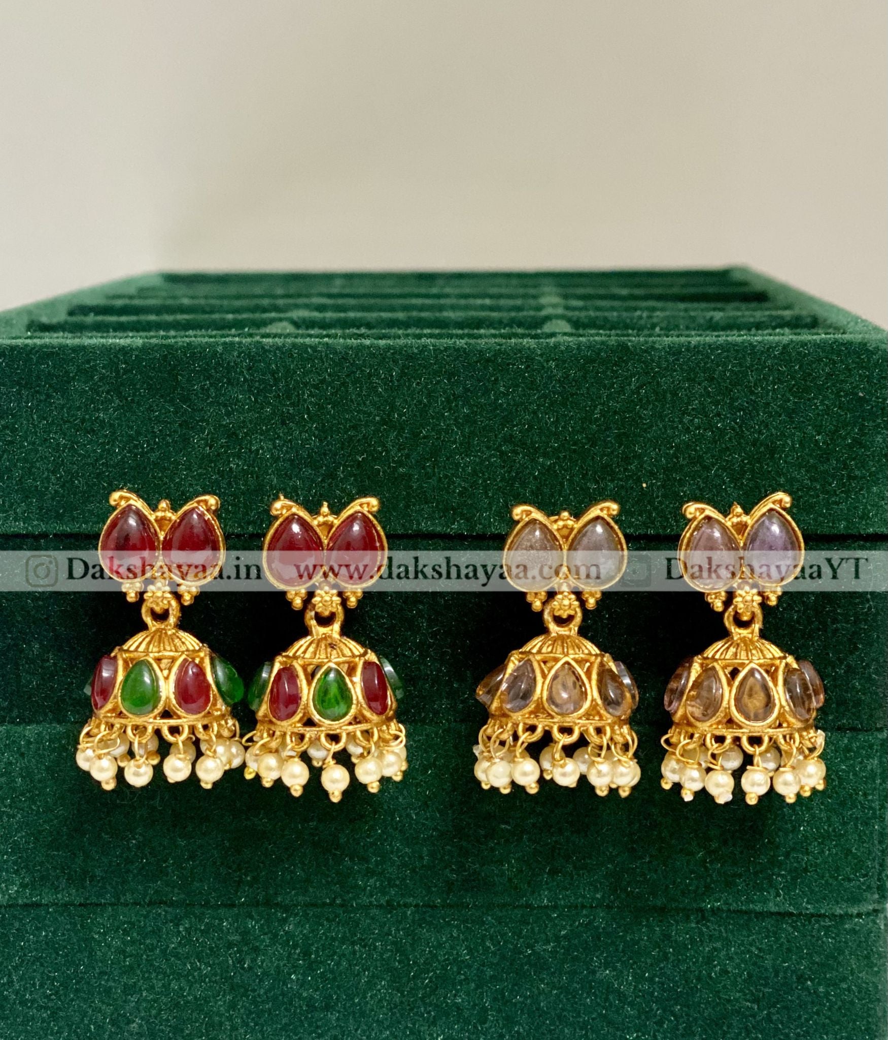 Set of gold earrings with gemstones on a green velvet background