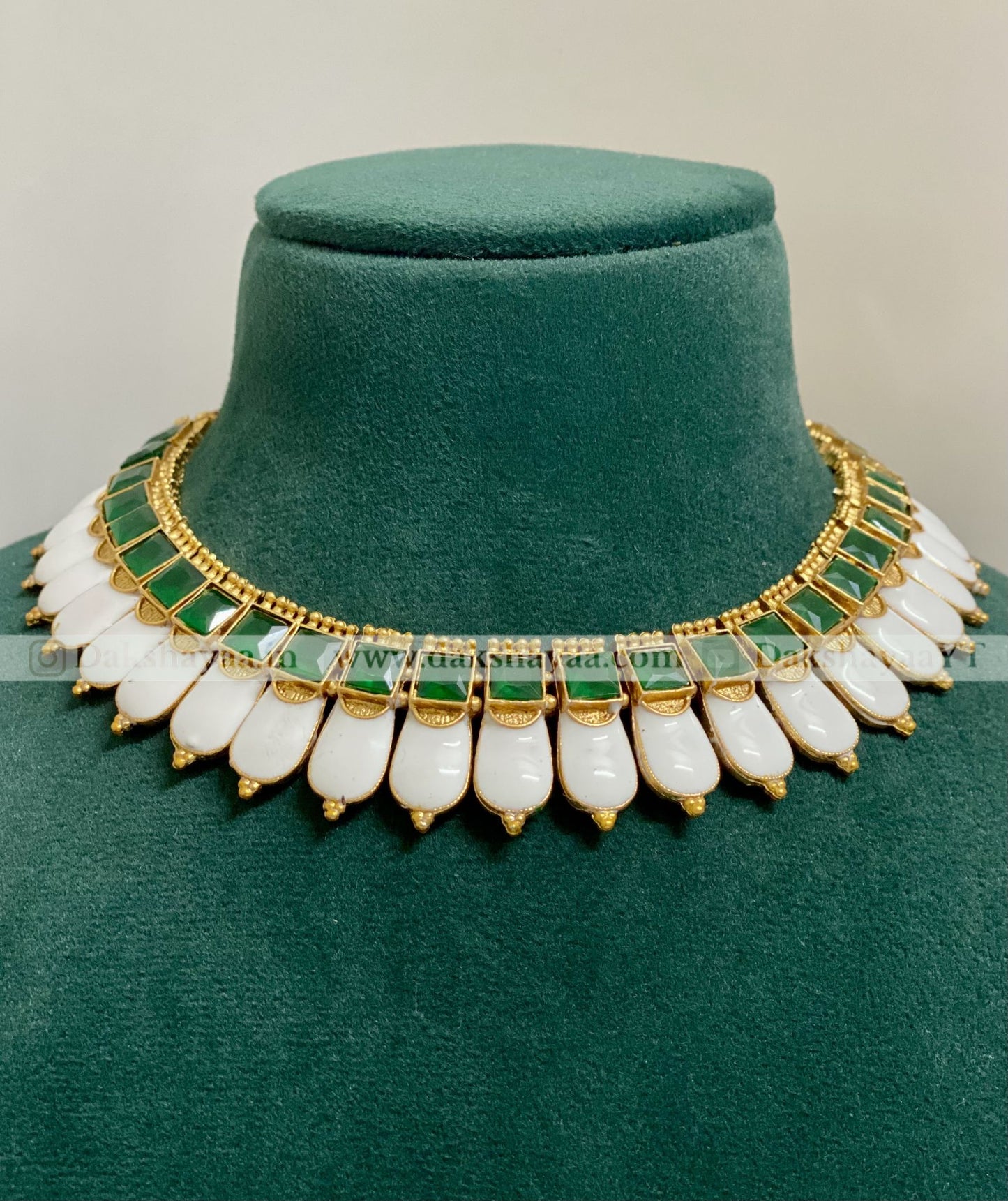 Decorative necklace with green and gold accents on a green cushion