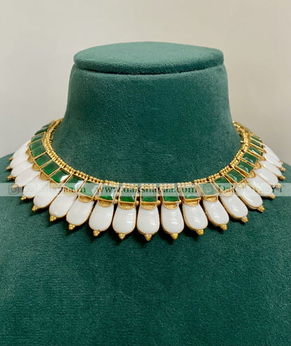 Decorative necklace with green and gold accents on a green cushion