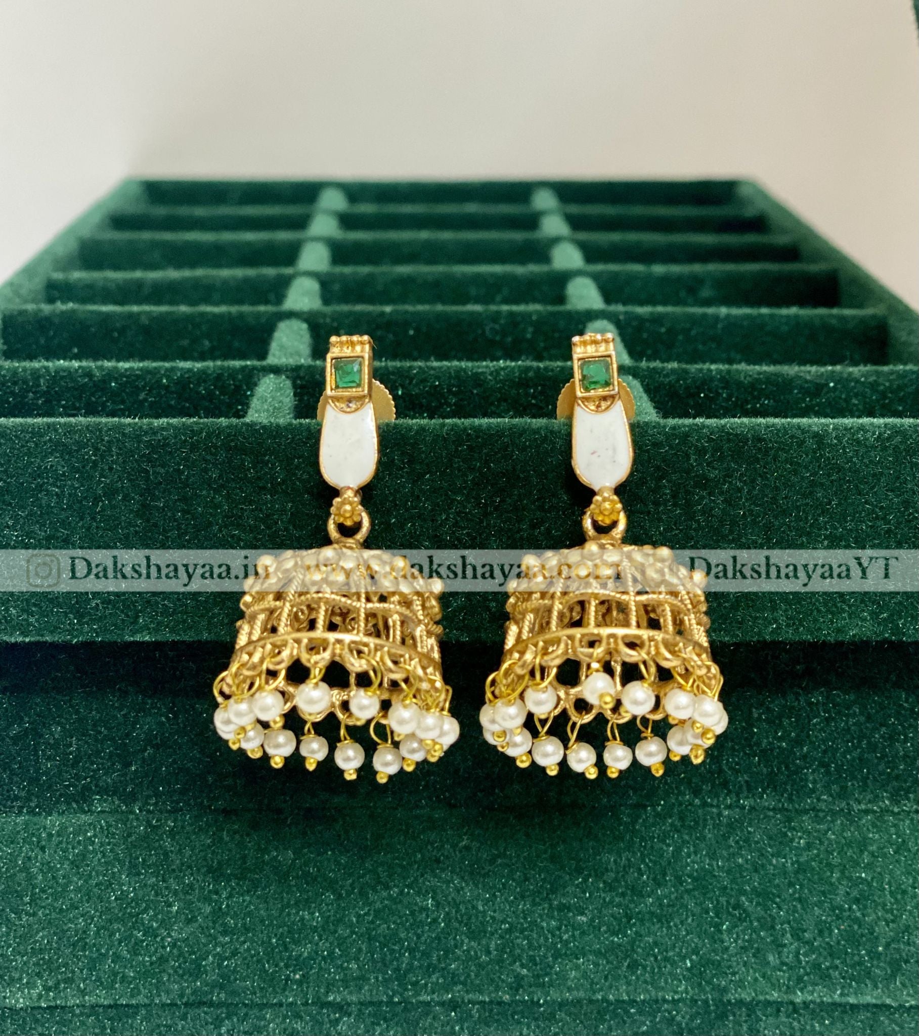 Gold and pearl earrings on a green velvet display box