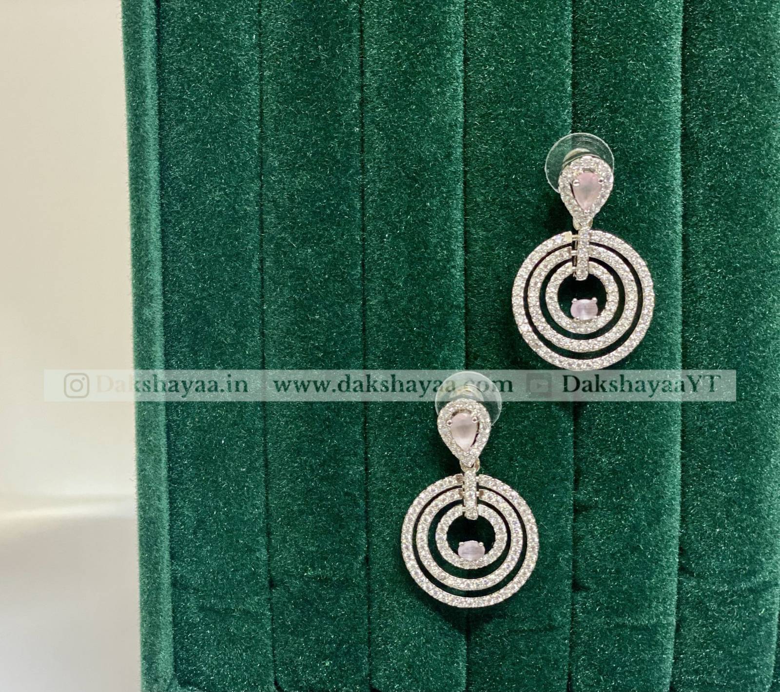 Silver earrings with circular design on a green velvet background
