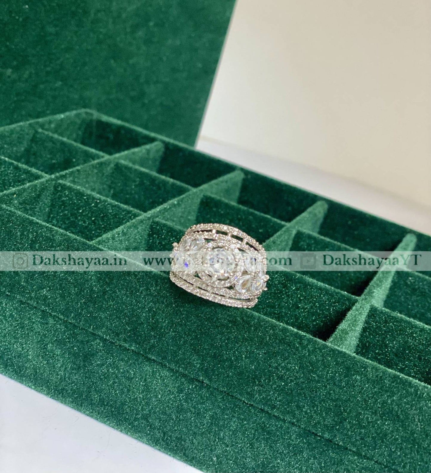 Silver ring with gemstones on a green velvet jewelry box