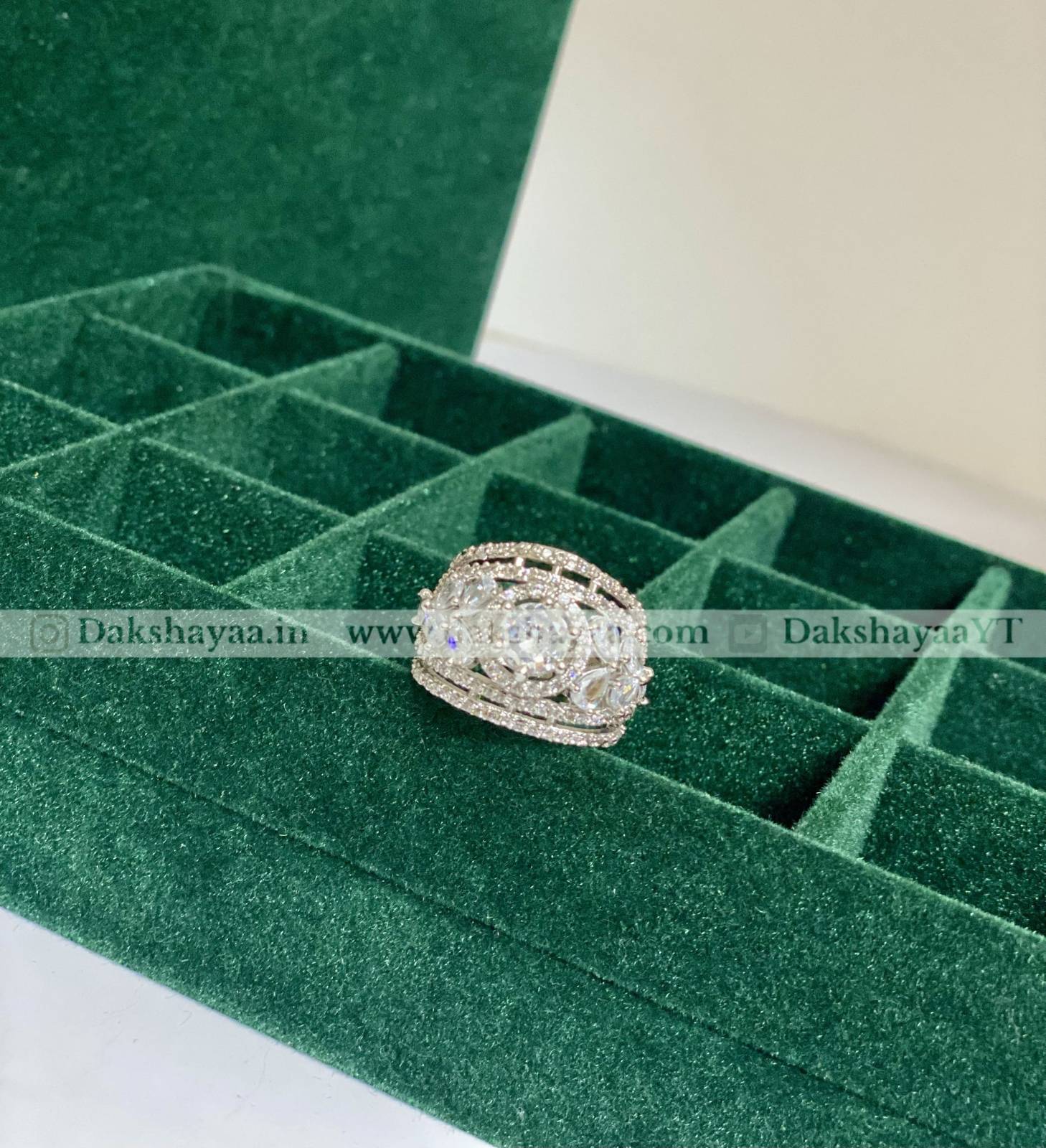 Silver ring with gemstones on a green velvet jewelry box